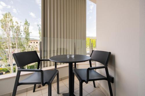 a table and two chairs on a balcony with a window at APARTAMENTS LA CARPA in Banyoles