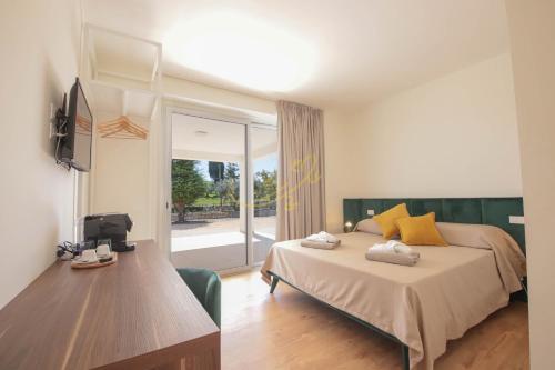 a bedroom with a bed and a desk and a television at Alberobbè luxury rooms in Alberobello
