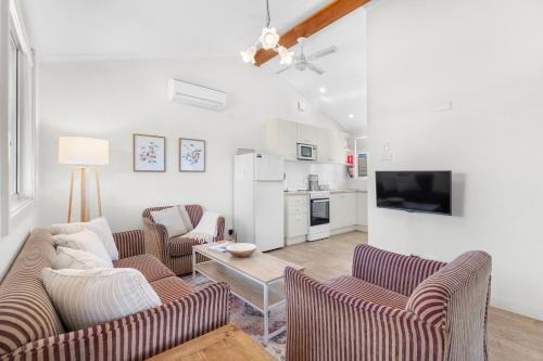 a living room with two couches and a kitchen at Madigan Cottages - The Kookaburra Cottage in Lovedale