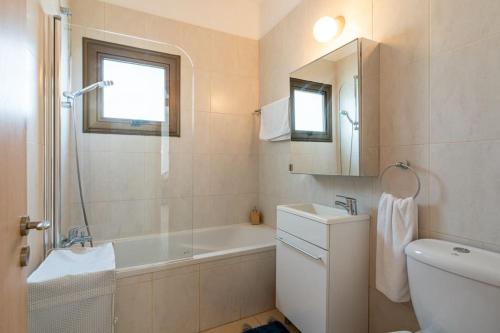 a bathroom with a tub and a sink and a mirror at Lumina 2-Bedroom Villa and Pool in Ayia Napa in Ayia Napa