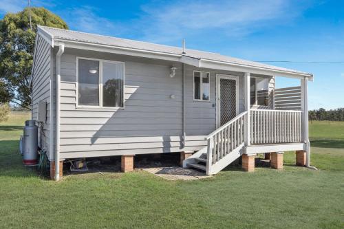 a gray tiny house with a porch and stairs at Madigan Cottages - The Kookaburra Cottage in Lovedale