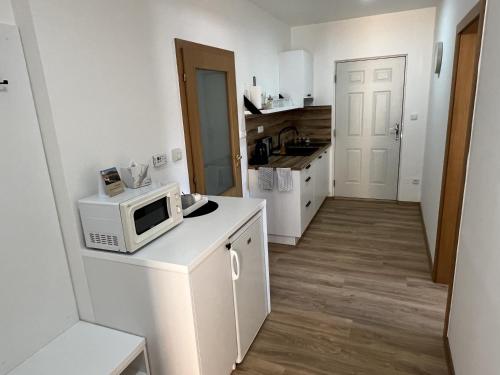 a small white kitchen with a microwave on a counter at Pension Mikulov in Mikulov