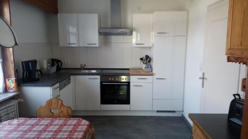 uma pequena cozinha com armários brancos e um fogão em Ferienhaus in ruhiger Lage mit großem Garten em Orsingen-Nenzingen