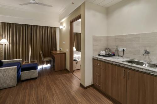 een keuken met een wastafel en een kamer met een bed bij Starlit Suites Newtown Kolkata in kolkata