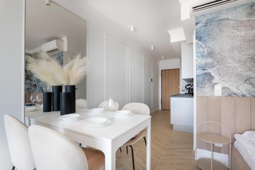 una sala da pranzo bianca con tavolo e sedie bianchi di Solaris Sea View a Darlowko