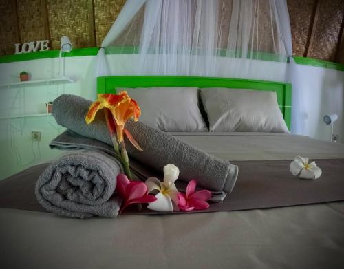 ein Bett mit Handtüchern und Blumen darüber in der Unterkunft Kaktus bungalow 4 in Gili Air