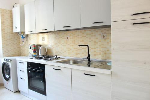 a white kitchen with a sink and a stove at Cilento Casa Vacanza Giuvino in Castelnuovo Cilento