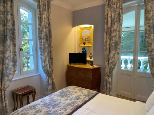 a bedroom with a bed and a dresser and windows at Logis Vélès in Aubin
