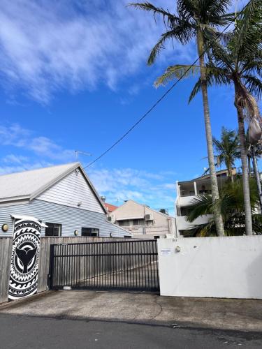 a white house with a fence and palm trees at Sophie's Place ReLaunch - Luxury Penthouse in Byron Bay