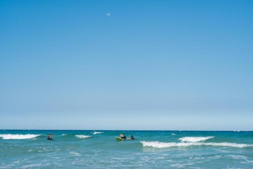 a group of people riding waves on surfboards in the ocean at The View Hotel in Cam Lâm