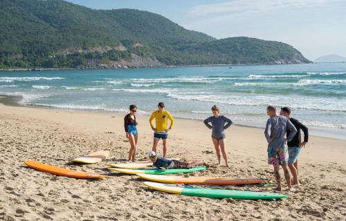 a group of people standing on a beach with surfboards at The View Hotel in Cam Lâm