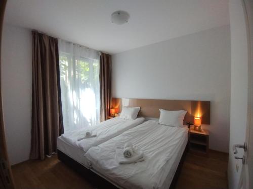 um quarto com uma cama com lençóis brancos e uma janela em Apartament Messambria Resort - Bastet BS em Sunny Beach