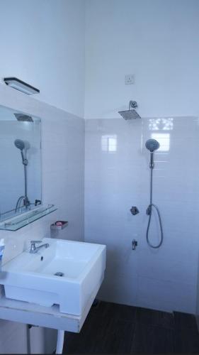 a white bathroom with a sink and a shower at Ananthaya-The infinity-kalutara 1br in Kalutara