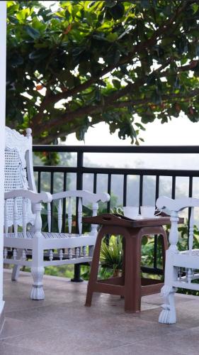 two white benches and a table next to a fence at Ananthaya-The infinity-kalutara 1br in Kalutara