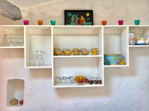 un mur avec des étagères blanches remplies de verrerie dans l'établissement CANNES CENTRE CHARMANT 2 ROOMS+MEZZANIN, à Cannes