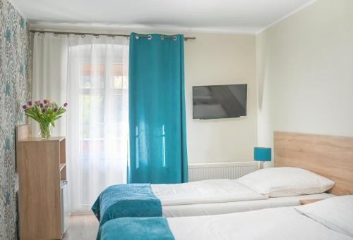 a bedroom with a bed and a blue curtain at Sanatorium Uzdrowiskowe Chemik in Duszniki Zdrój