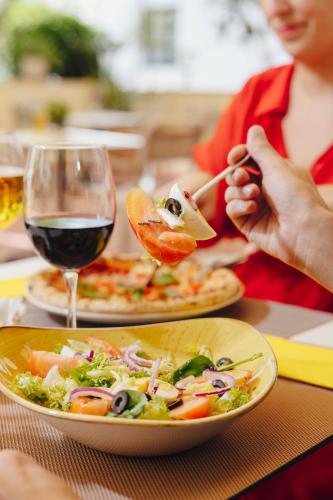 a woman sitting at a table with a plate of food and a salad at Ibis Sevilla in Seville