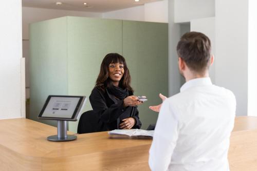 a woman talking to a man in a room at Fred Hotel Zürich Hauptbahnhof in Zürich