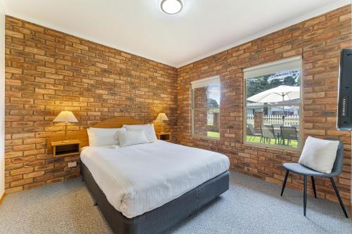 a bedroom with a bed and a brick wall at BIG4 Tasman Holiday Parks - Warrnambool in Warrnambool