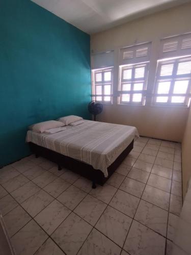- une chambre avec un lit aux murs bleus et des fenêtres dans l'établissement Casa da Nanda, à Fortaleza