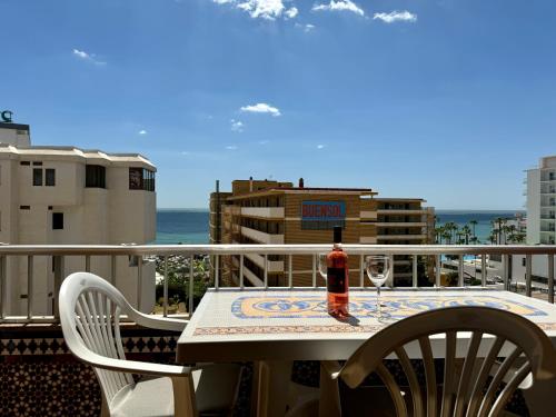 托雷莫利諾斯的住宿－La Carihuela a 150 metros de la playa con espectaculares vistas，阳台上的桌子上摆放着一瓶葡萄酒