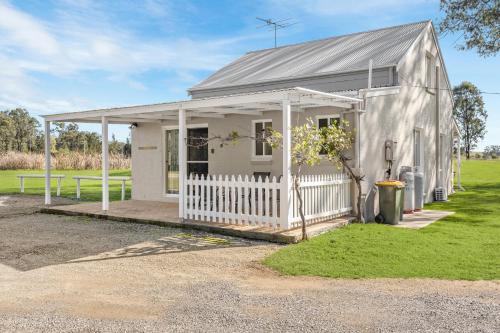 a small white house with a white fence at Madigan Cottages - Settlers Cottage in Lovedale