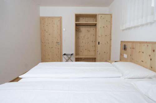 a white bed in a room with wooden doors at Chasa Helvetia Duai in Müstair