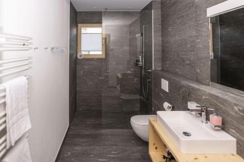 a bathroom with a sink and a shower and a toilet at Chasa Helvetia Duai in Müstair