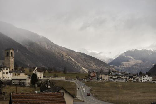 a town with a road in front of a mountain at Chasa Helvetia Trai in Müstair