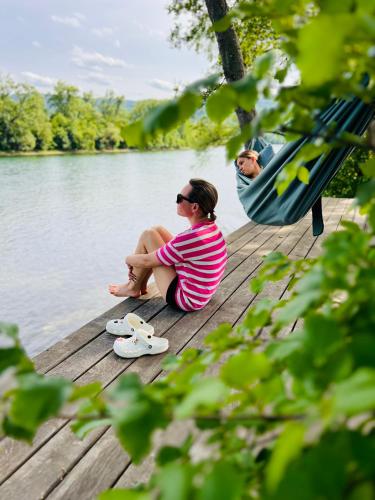 a woman sitting on a dock next to the water at Nova Drina in Ljubovija