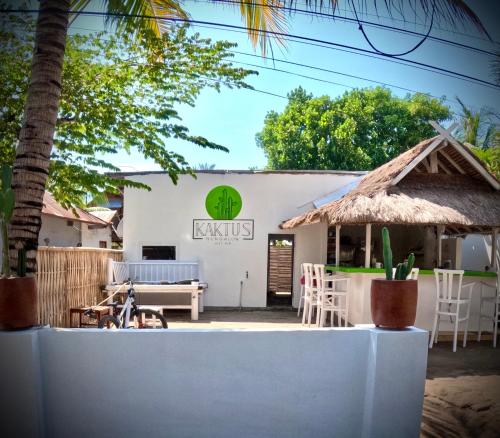 ein Restaurant mit einem weißen Gebäude mit einem Grasdach in der Unterkunft Kaktus bungalow 3 in Gili Air