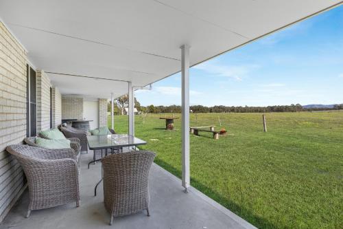a patio with a table and chairs and a field at Madigan Cottages - The Homestead in Lovedale