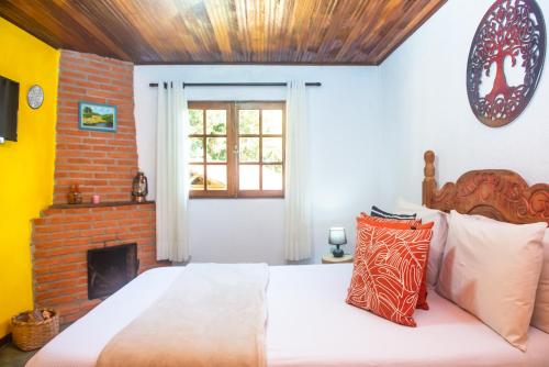 a bedroom with a bed and a brick fireplace at Chalés Recanto da cachoeira in Monte Verde
