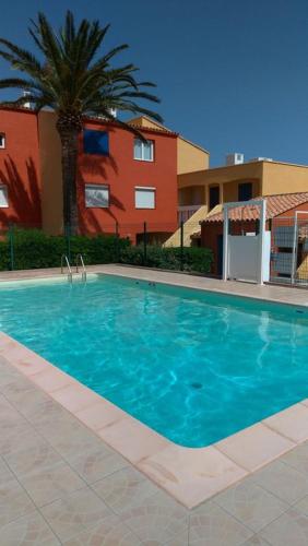 une grande piscine bleue devant un immeuble dans l'établissement Nautica bulles jacuzzi privatif vue lac marin, au Barcarès