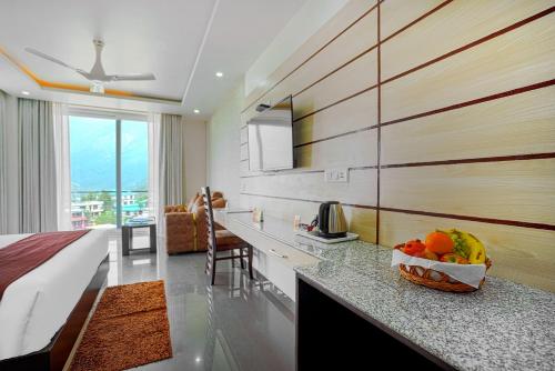 a room with a bed and a bowl of fruit on a counter at Aliza Inn And Suites By SRS Hotels in Dharamshala