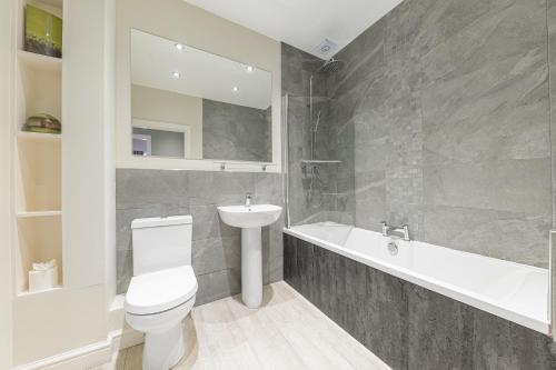 a bathroom with a toilet and a sink and a bath tub at Abbey Apartments Modern ApartHotel for Tourists & Professionals in Barrow in Furness
