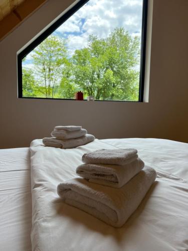 una pila de toallas sentadas en una cama con ventana en Nova Drina, en Ljubovija