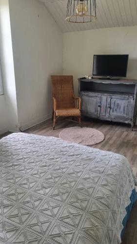 1 dormitorio con 1 cama, 1 silla y TV en La vergne, en Mézières-sur-Issoire