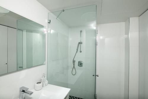 uma casa de banho branca com um chuveiro e um lavatório. em סיסייד אילת חדר עם נוף לים - Seaside Eilat Room With Sea View em Eilat
