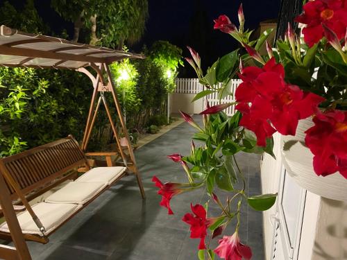 un patio con un banco y flores rojas en Conteamare, en Marina di Modica