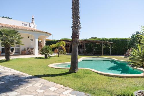 a villa with a swimming pool and a palm tree at The Lighthouse Hostel in Sagres