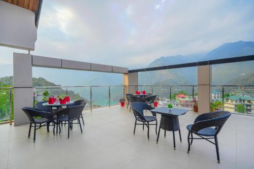 a balcony with tables and chairs and a view of mountains at Aliza Inn And Suites By SRS Hotels in Dharamshala
