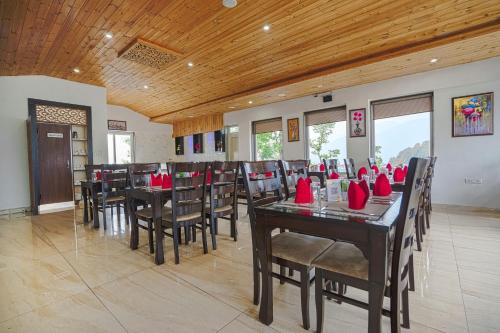 a dining room with tables and chairs with red napkins at Aliza Inn And Suites By SRS Hotels in Dharamshala