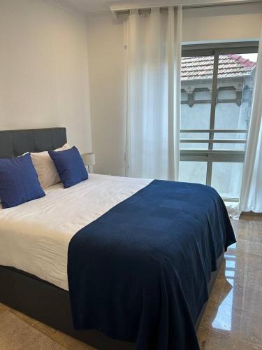 a bedroom with a bed with blue sheets and a window at REGIDOR Cartagena in Cartagena