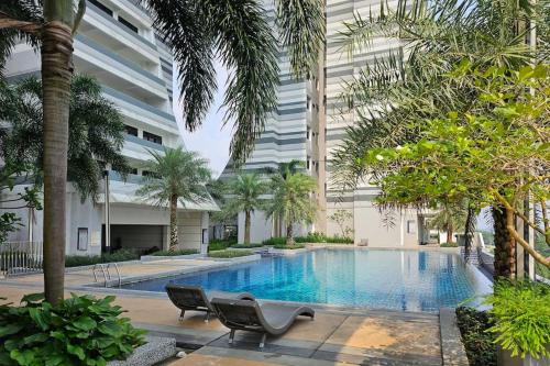 a swimming pool with two chairs and a building at Meridin Medini, Iskandar Puteri, Johor in Nusajaya