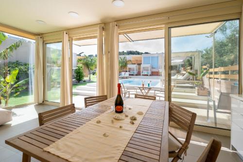 a dining room with a table with a bottle of wine at Modular Bungalows With Heated Pool Artemis Greece in Artemida