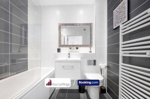 Baño blanco con lavabo y espejo en St Mary's Retreat By Your Lettings Short Lets & Serviced Accommodation Peterborough With Free WiFi,Parking And More, en Huntingdon