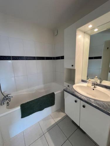 une salle de bain blanche avec une baignoire et un lavabo dans l'établissement Joli appartement avec balcon, à Caen