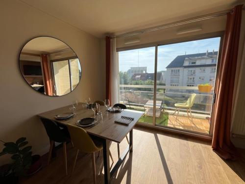 une salle à manger avec une table et une grande fenêtre dans l'établissement Joli appartement avec balcon, à Caen