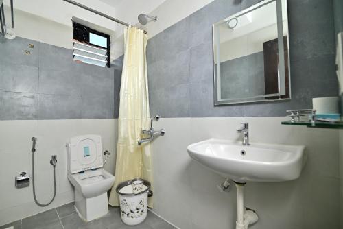 a bathroom with a sink and a toilet and a mirror at Q lite Calangute in Calangute